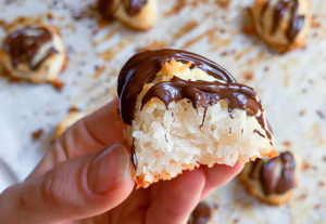 Chocolate covered coconut macaroons held in hand